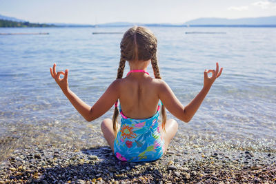 Girl practicing lotus position near seashore