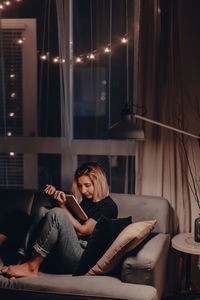 Young woman sitting on sofa at home