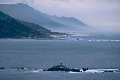 Scenic view of sea by mountains against sky