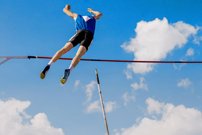 Low angle view of man jumping against sky