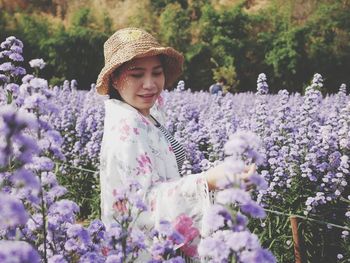 Portrait of smiling woman standing by purple flowering plants