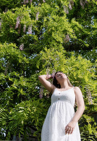 Portrait of young woman standing against plants
