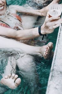 Low section of woman with people in swimming pool