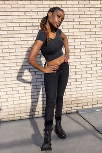 Young woman standing against brick wall