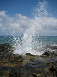 Close-up of waves splashing on beach against sky