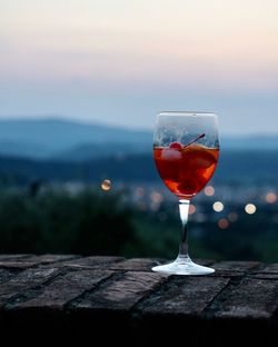 Close-up of wine glass on table against sky during sunset