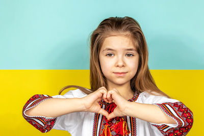 Portrait of young woman standing against yellow background