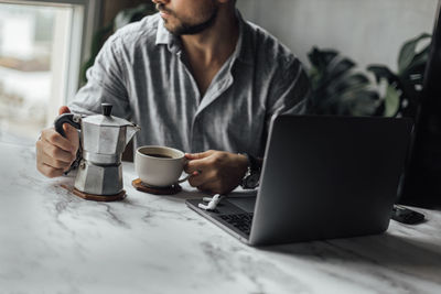 Midsection of man using laptop at table