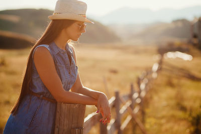 Side view of woman standing by railing on field