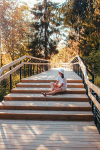 Woman sitting on wooden footbridge