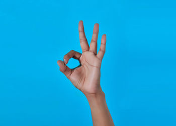 Close-up of person hand against blue background