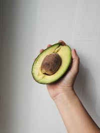 Midsection of person holding fruit against wall