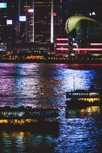 Illuminated modern buildings by river at night