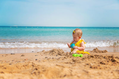 Cute baby girl playing with toy at beach