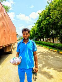 Portrait of young man standing against blue sky