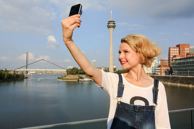 Woman taking selfie with mobile phone against sky