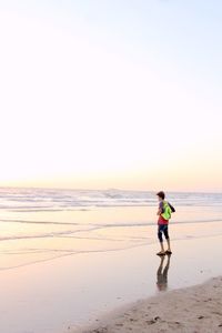 Full length of man on beach against sky during sunset