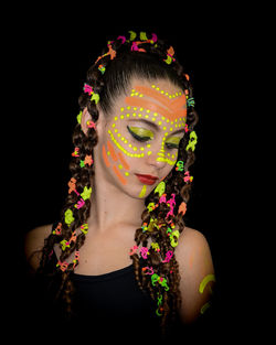 Close-up of young woman against black background