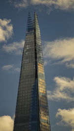 Low angle view of skyscrapers against cloudy sky