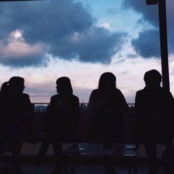 Silhouette of people against cloudy sky