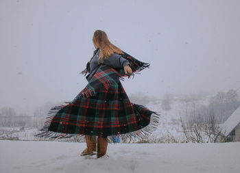 Woman with umbrella standing in amusement park during winter