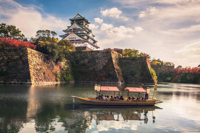 Boat in river by building against sky