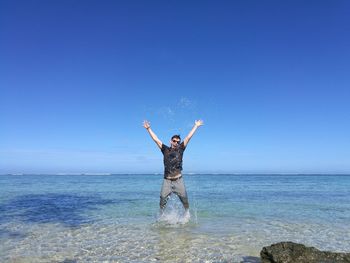 Man jumping in sea against clear blue sky
