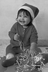 Cheerful baby girl playing with illuminated string lights during christmas at home