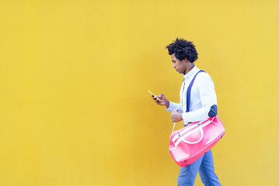 Side view of woman standing against blue background