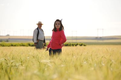 Girl standing on field against sky