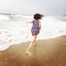 Rear view of girl running on shore at beach