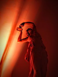 Side view of woman standing against red wall