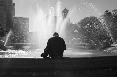 Rear view of man on fountain in city