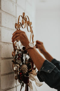 Close-up of man holding hanging against wall