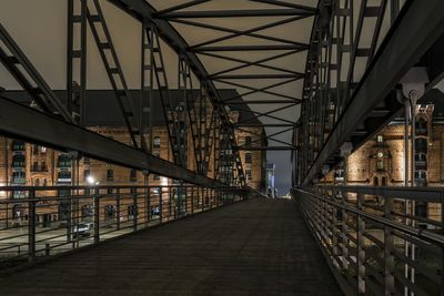 Footbridge against buildings at night