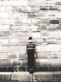 Rear view of man standing against brick wall