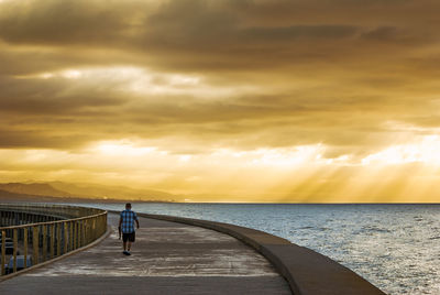 Man standing on beach against sky during sunset