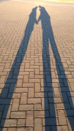 Low section of man shadow on tiled floor