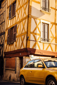 Yellow car against sky in city