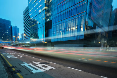 Light trails on road by buildings in city