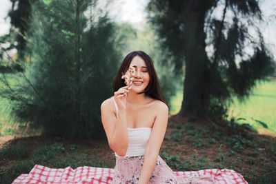 Portrait of a smiling young woman sitting on land