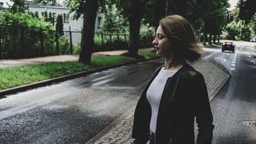 Side view of teenage girl standing on road in city