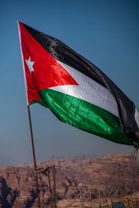 Low angle view of flag against clear blue sky