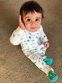 Portrait of cute smiling boy sitting on rug at home