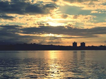 Scenic view of river against cloudy sky during sunset