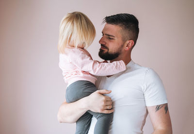 Young father with baby girl on hands at home