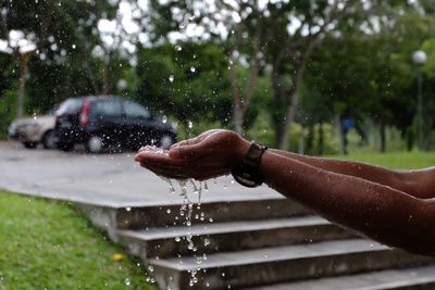 Cropped image of hands collecting raindrops