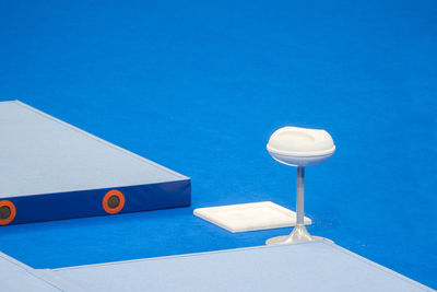 Close-up of white table and swimming pool against blue sky