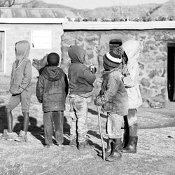 Rear view of people standing against wall