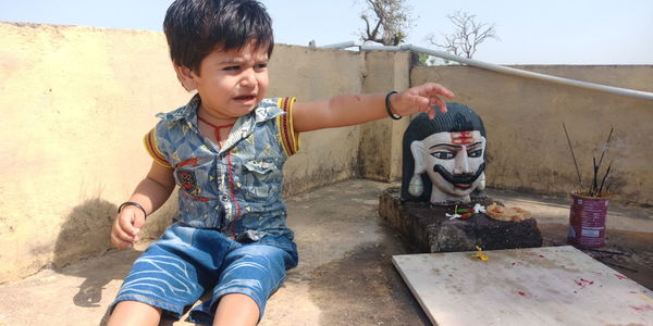 Boy crying while gesturing by wall